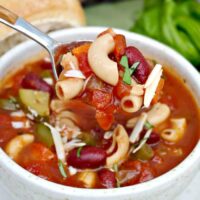 A cream bowl full of minestrone soup