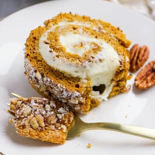 A slice of pumpkin roll cake on a white plate.