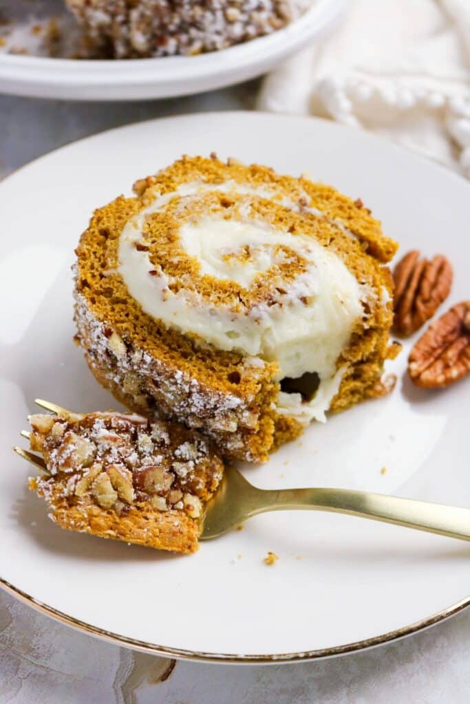 A slice of pumpkin roll cake on a white plate.