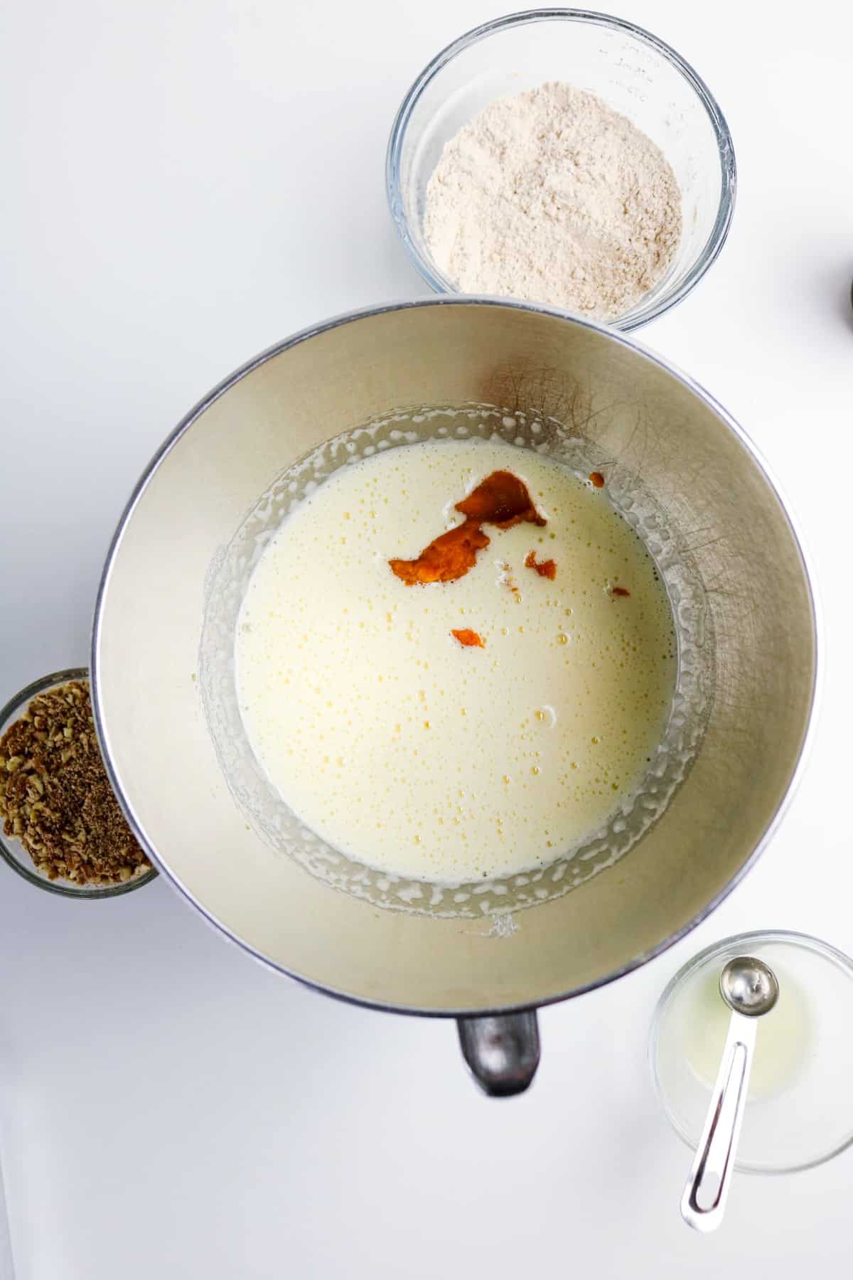 Pumpkin puree added to egg mixture in a mixing bowl.