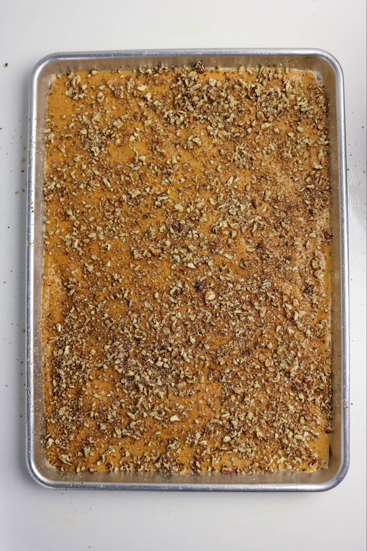 Pumpkin cake batter topped with pecans before baking.