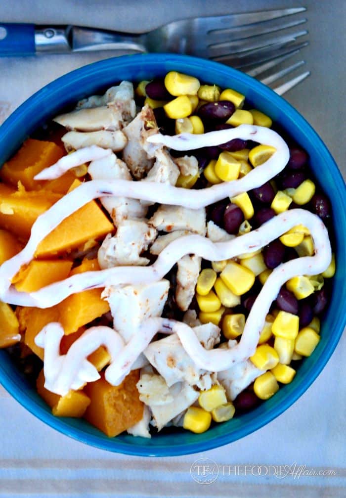 Healthy Quinoa Burrito Bowl layered with roasted butternut squash, black beans, corn and chicken. topped with a yogurt salsa Ranchera sauce. The Foodie Affair