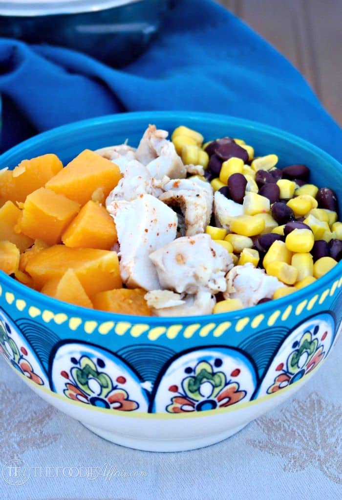 Healthy Quinoa Burrito Bowl layered with roasted butternut squash, black beans, corn and chicken. topped with a yogurt salsa Ranchera sauce. The Foodie Affair