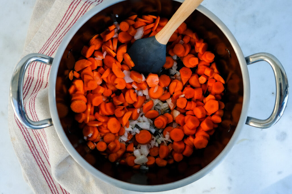 Diced carrots and onion sautéing in a stockpot. 