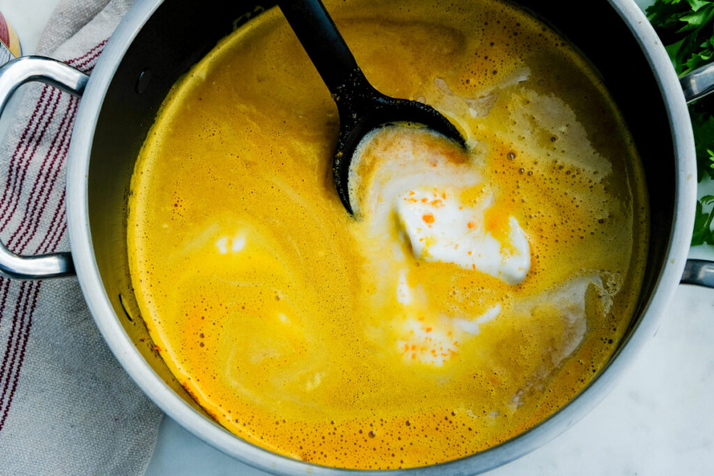 Coconut milk added to blended carrot soup.