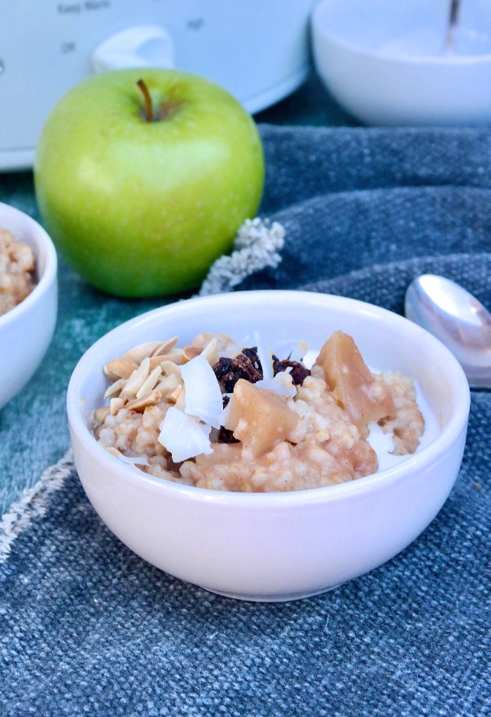 A white bowl with oatmeal topped with coconut flakes and nuts. 