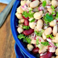 Three bean salad with a light dressing in a blue serving bowl