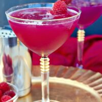 raspberry syryp cocktail in a martini glass on a gold plate