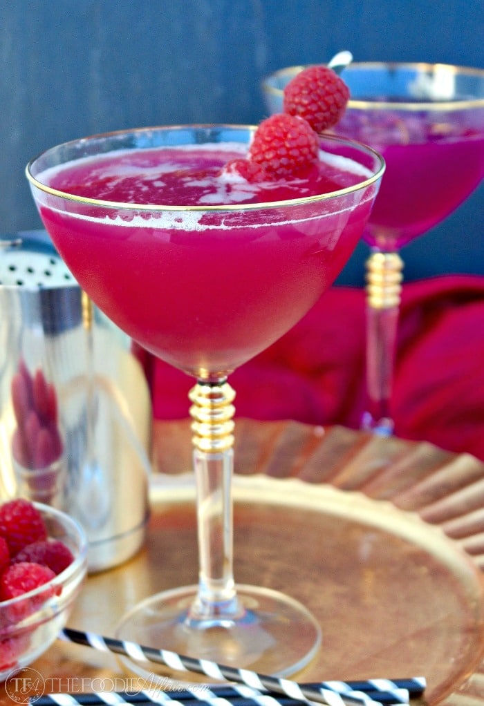 raspberry syryp cocktail in a martini glass on a gold plate
