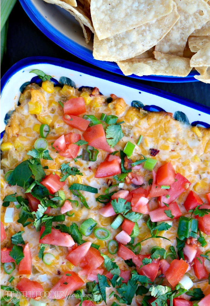 This Hot Cheesy Corn Dip is baked with a creamy yogurt base folded with cheese, sweet corn, green chilis, and then topped with fresh vegetables! Easy and delicious! The Foodie Affair