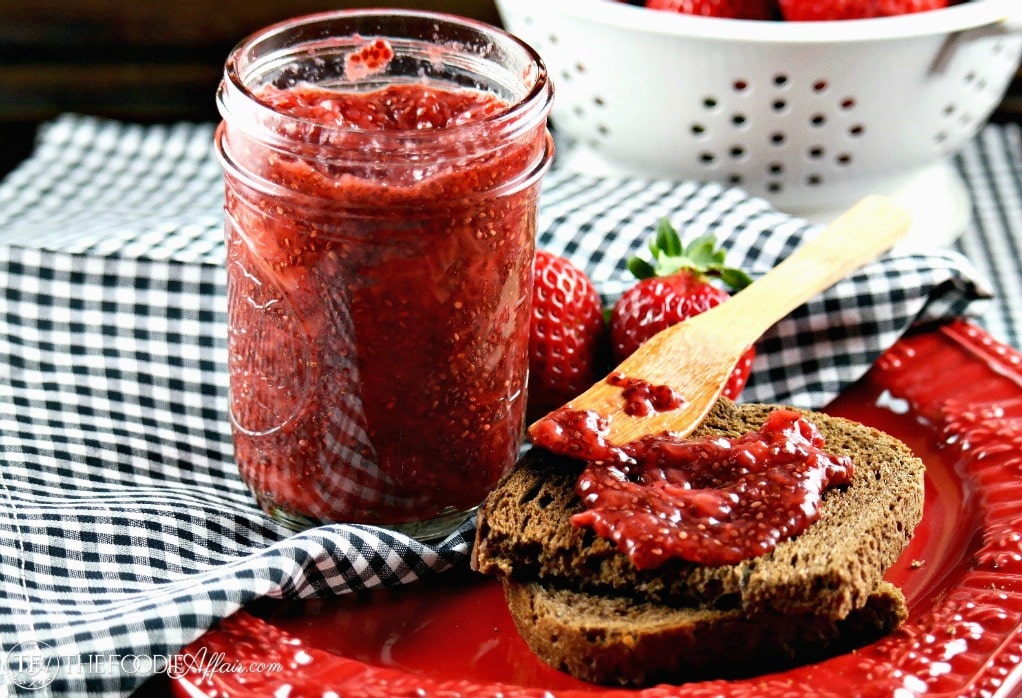 Strawberry Chia Jam in a clear mason jar with a black and white napkin on a red plate