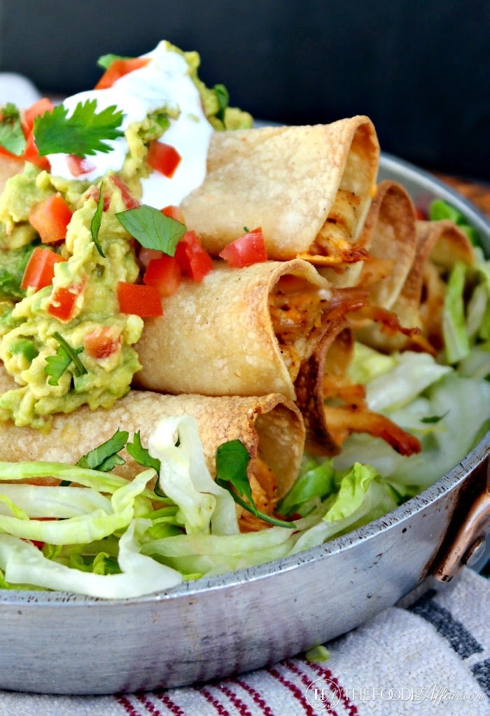 Baked Chicken Taquitos topped with guacamole and sour cream