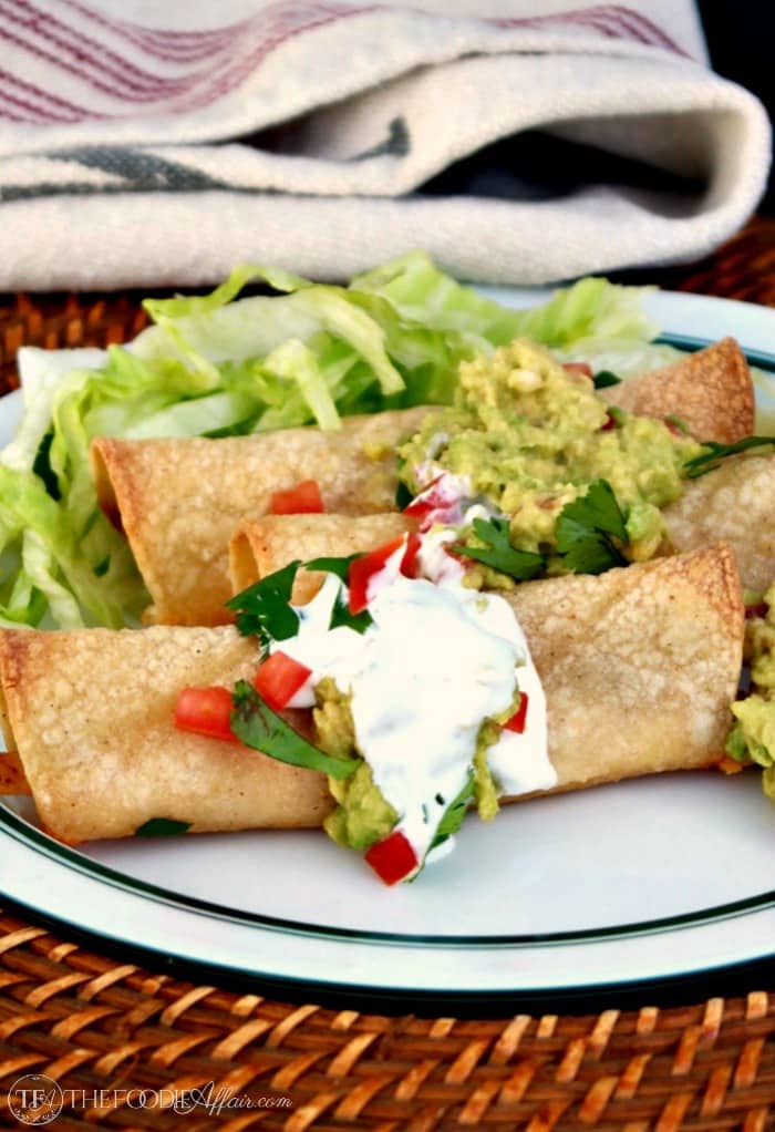 Baked Chicken Taquitos on a white plate with a green rim
