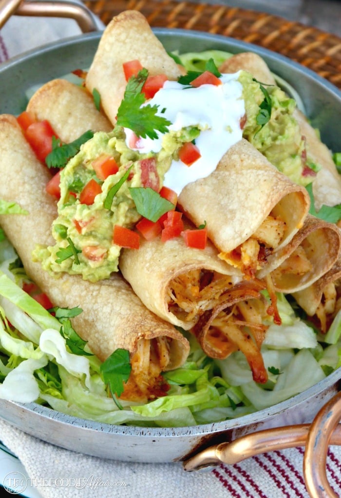 Baked Chicken Taquitos filled with seasoned shredded chicken and cheese comes together quickly when baked in the oven instead of fried. Add your favorite toppings and enjoy at your next fiesta! The Foodie Affair