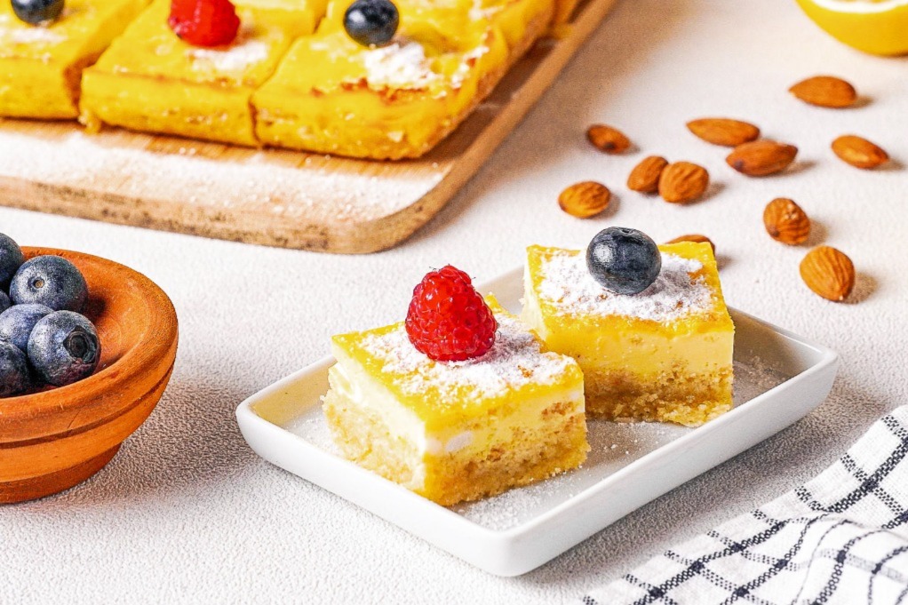 Lemon bars on a white plate topped with berries. 