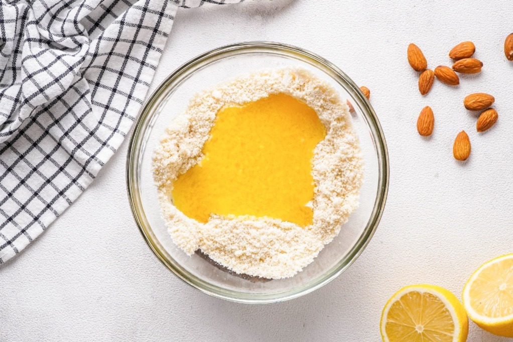 A clear mixing bowl with almond flour and butter.