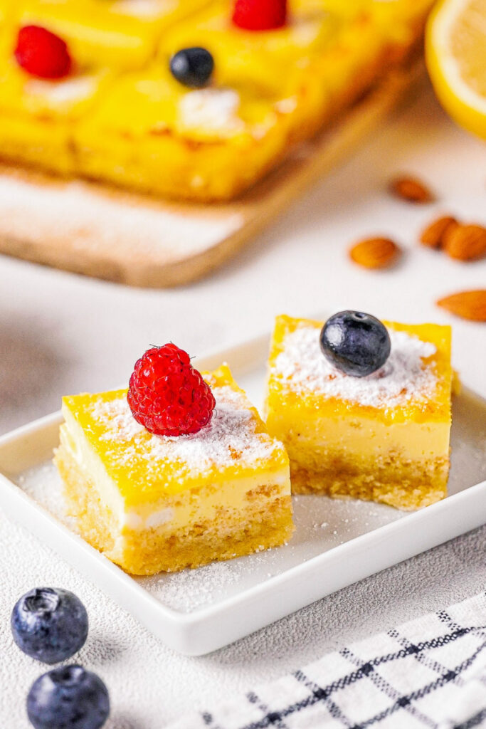 Keto lemon bars on a white plate with a fresh fruit garnish.