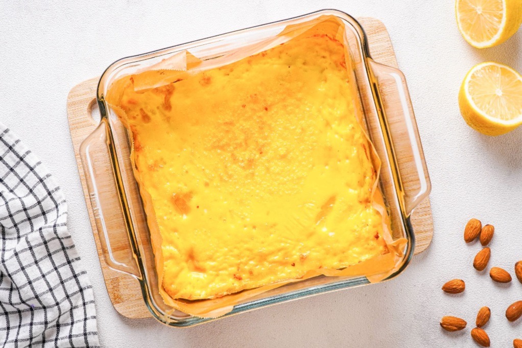 Baked lemon bars in a baking dish lined with parchment paper.