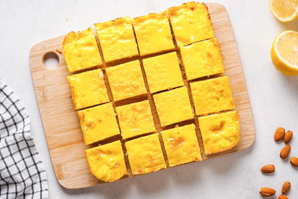 Lemon bars on a cutting board cut into squares. 