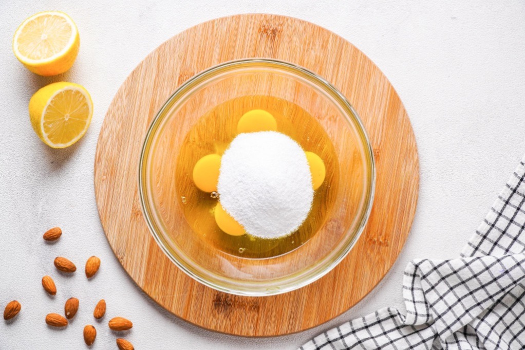 Eggs and sugar in a mixing bowl before beating together.