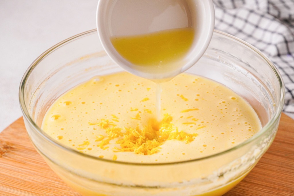 Lemon filling with fresh lemon juice in a mixing bowl before pouring over crust.