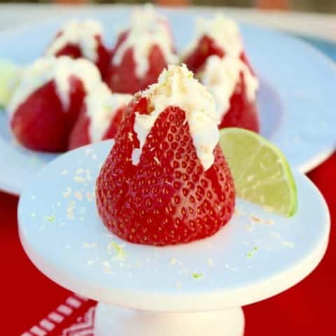 Cheesecake Stuffed Strawberries with coconut on a white pedestal