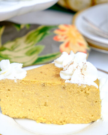 A slice of low Carb pumpkin cheesecake on a white plate with a gold rim ready to enjoy.