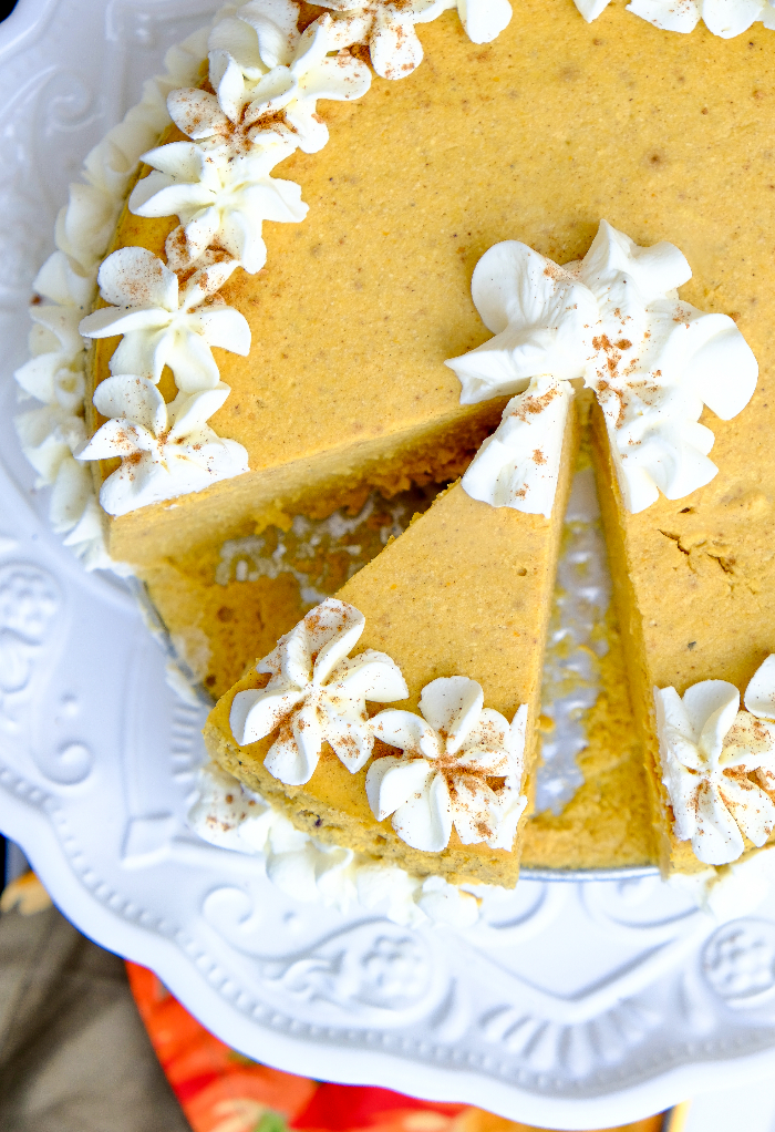 Sliced keto pumpkin cheesecake on a white cake platter.