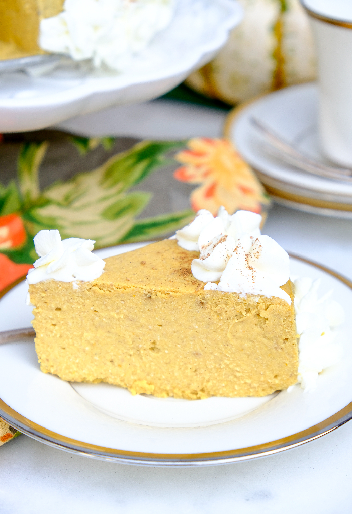 Slice of low carb keto pumpkin cheesecake topped with whipped cream. 