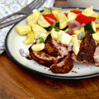 Sliced pork tenderloin with pineapple salsa on a white plate.