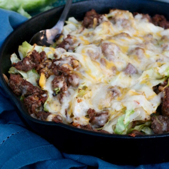 Ground beef and cabbage in a cast iron skillet topped with cheese.