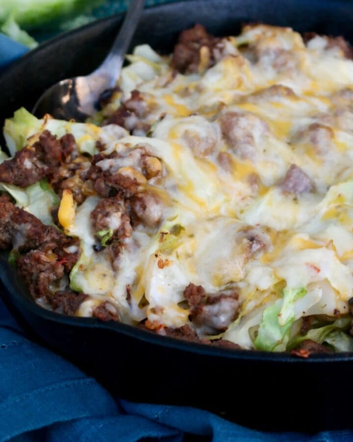 Ground beef and cabbage in a cast iron skillet topped with cheese.