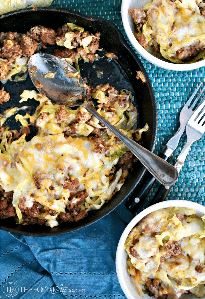 cabbage beef skillet recipe in a cast iron pan with two filled bowls