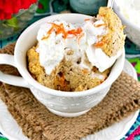 Low carb mug cake with whipped cream and shreds of carrots on top.