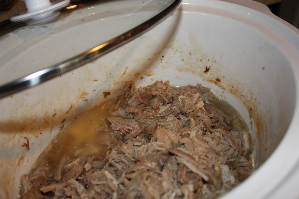 Kalua pork shredded in a white slow cooker ready to be eaten