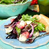 A light blue plate with strawberry avocado chicken salad on a blue napkin