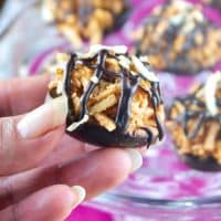 Holding with fingers copycat Samoas no bake cookies with coconut, caramel and dark chocolate. #nobake #cookies #Samoa | www.thefoodieaffair.com