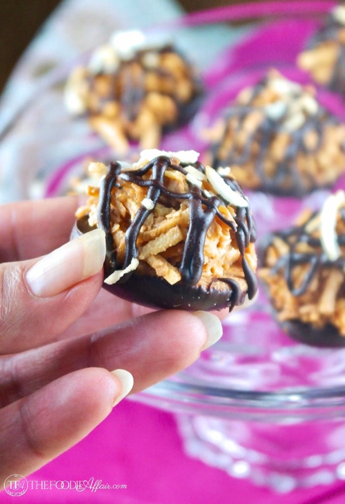 Holding with fingers copycat Samoas no bake cookies with coconut, caramel and dark chocolate. #nobake #cookies #Samoa | www.thefoodieaffair.com