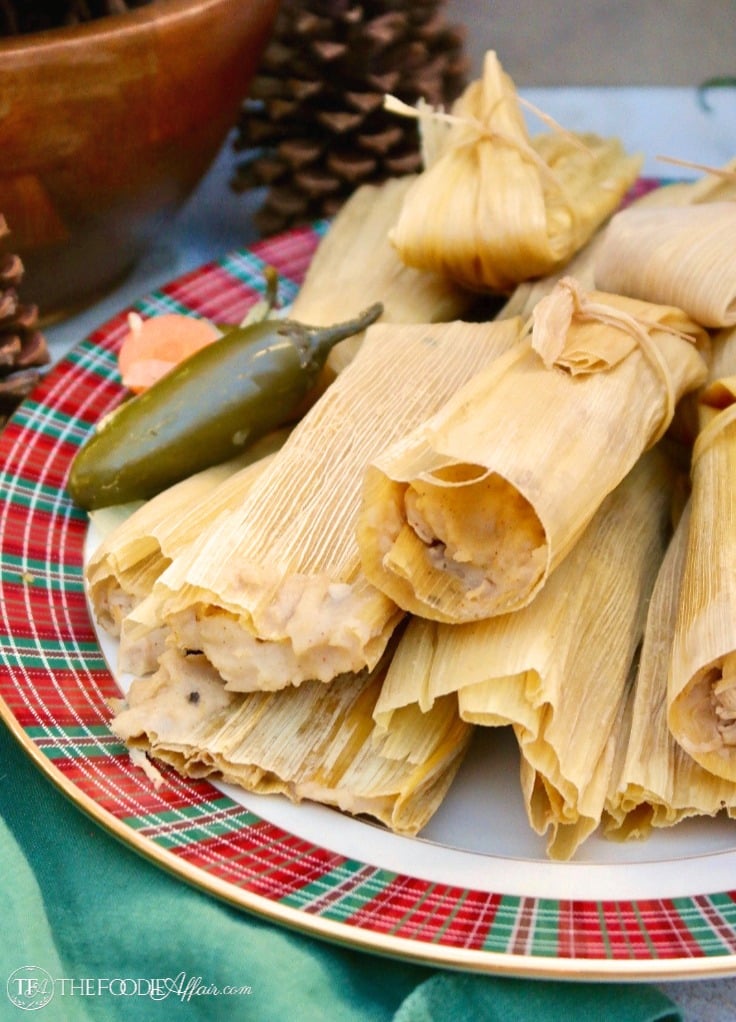 Homemade tamales in corn husk wraps on a plaid platter #tamales #homemade #recipe | www.thefoodieaffair.com