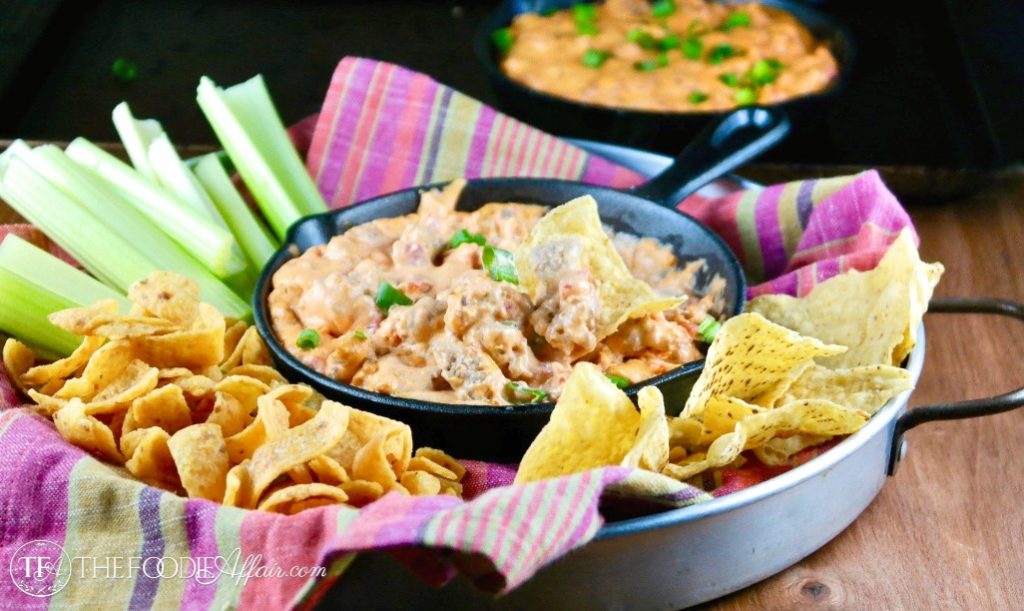 Appetizer tray with chips and celery sticks surrounded by a iron skillet of sausage queso dip #EasyRecipe #appetizer #Dip | www.thefoodieaffair.com