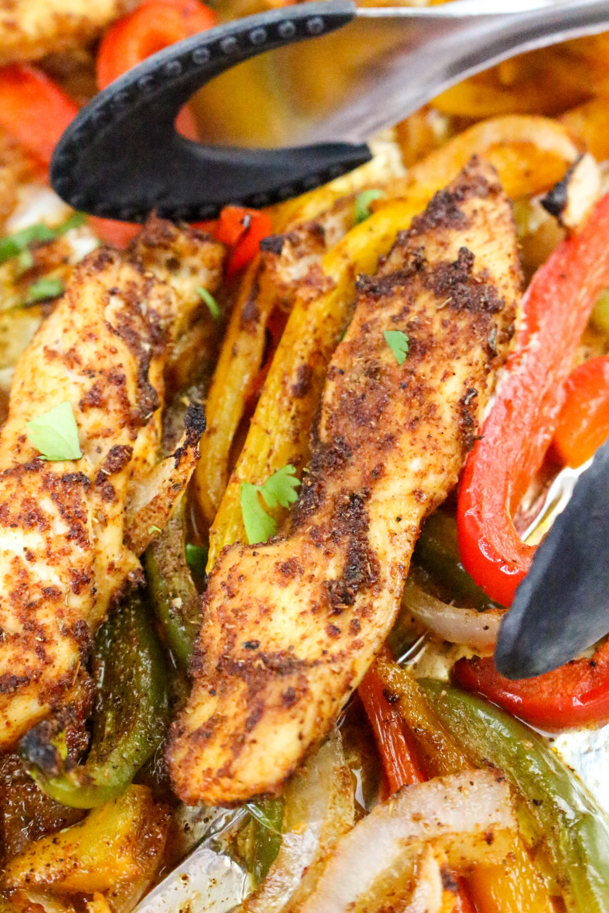 Chicken with bell peppers cooking on a sheet pan.