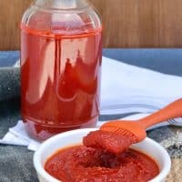 homemade low carb bbq sauce in a white bowl with orange baster