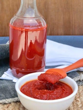 homemade low carb bbq sauce in a white bowl with orange baster