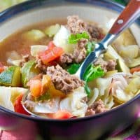 bowl of beef cabbage soup with a a wooden handle spoon