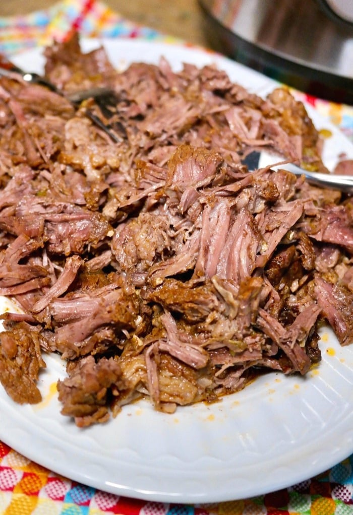 pulling apart beef with two forks for shredded beef dishes