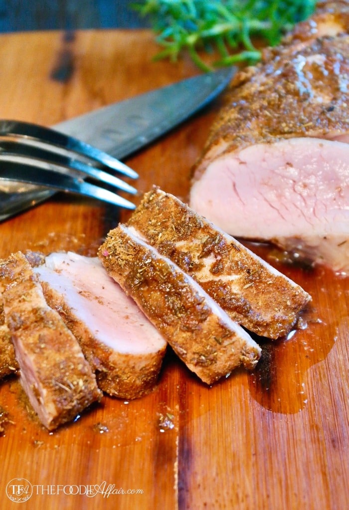 Sliced baked pork tenderloin on a brown cutting board