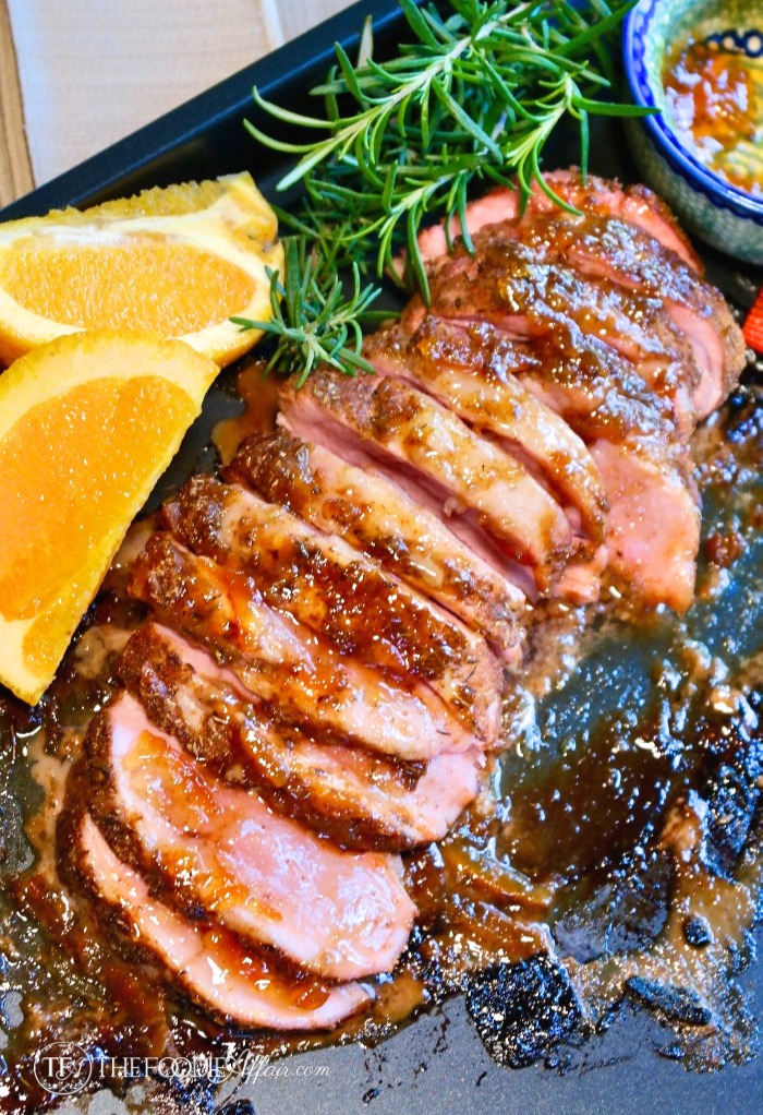 sliced baked pork tenderloin with orange marmalade on a baking sheet