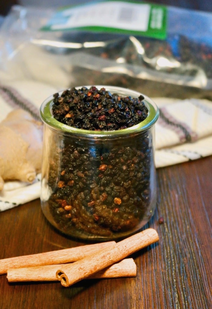 Dried elderberries in a clear glass jar for a homemade elderberry syrup recipe