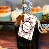 Homemade elderberry syrup recipe in a clear glass jar on a wooden table