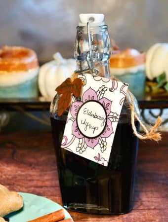 Homemade elderberry syrup recipe in a clear glass jar on a wooden table